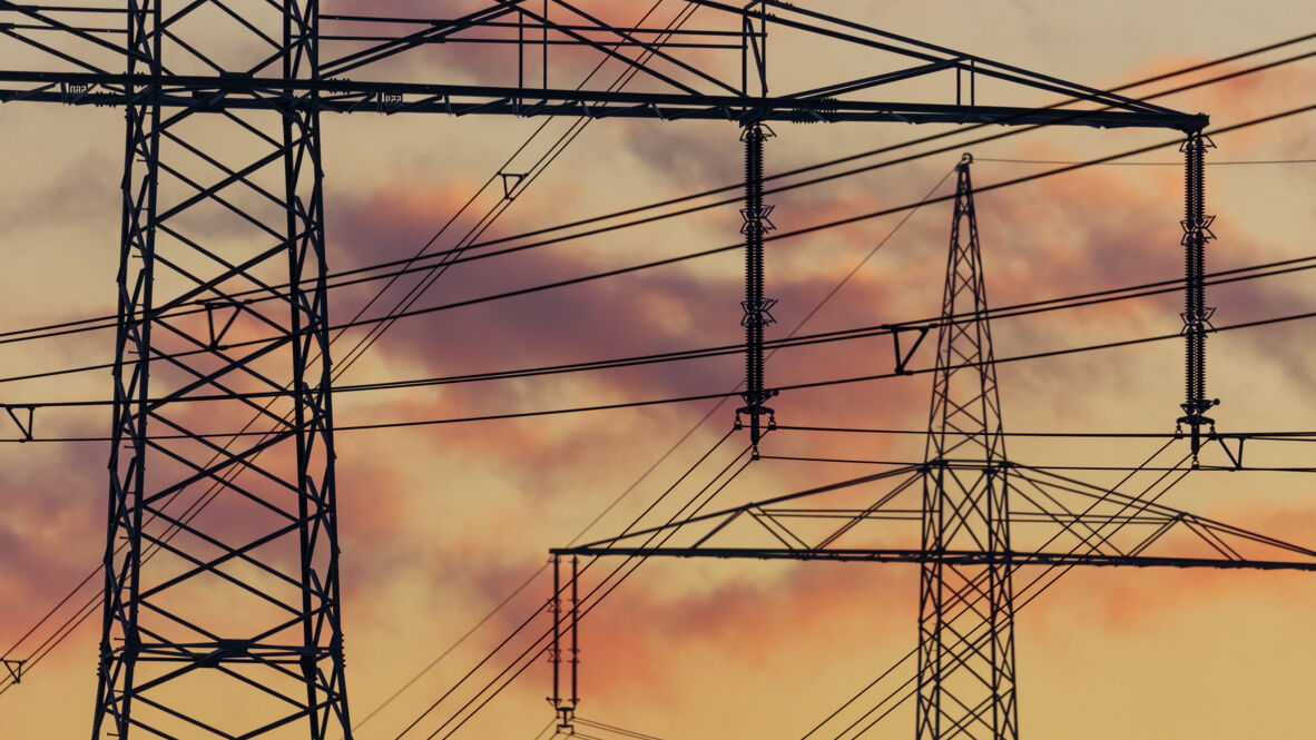 Hochspannungsleitungen und Gittermasten bei Sonnenuntergang – Cteam Anlagenbau für Energieinfrastruktur.