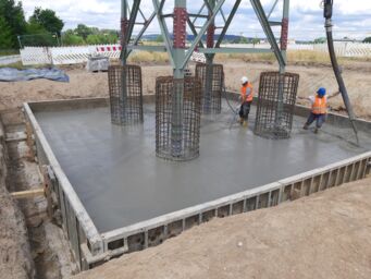 Cteam radnici betoniraju temelj za građevinsku konstrukciju s betonskom pumpom. Cteam radnici betoniraju temelj za građevinsku konstrukciju s betonskom pumpom.