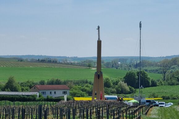 Vue d'une structure haute avec des vignes au premier plan et une équipe Cteam travaillant sur un projet extérieur.