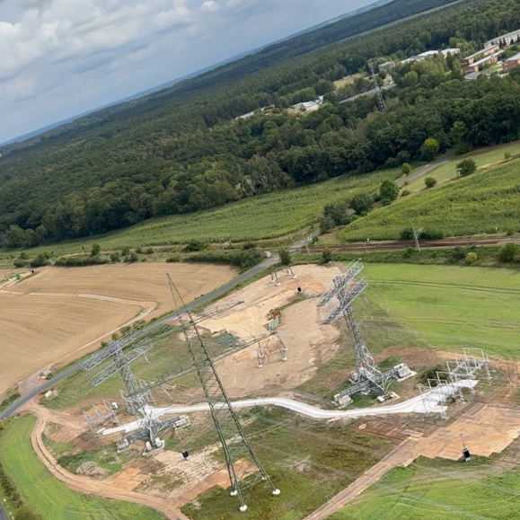 Luftaufnahme einer Cteam Freileitungsbau Baustelle mit Gittermasten im Bau.
