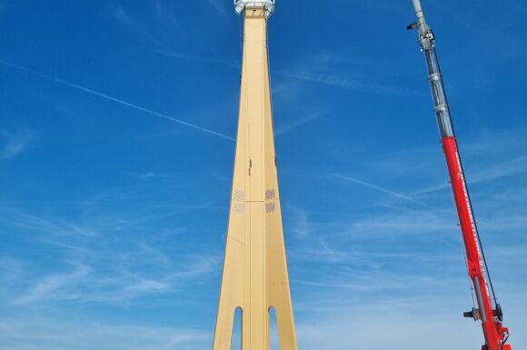 Cteam Consulting und Anlagenbau: Errichtung eines hohen Mastes mit Kran unter blauem Himmel.